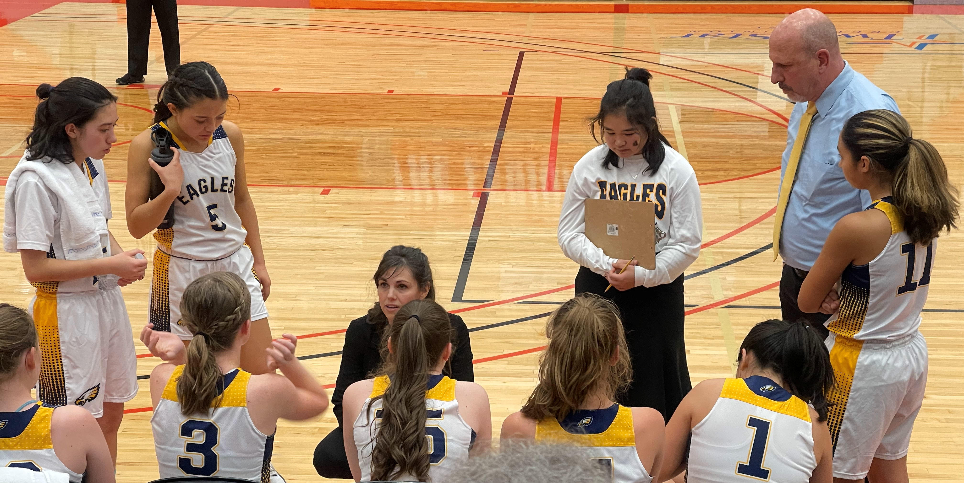 The girls basketball team huddles around their coach during a time out.