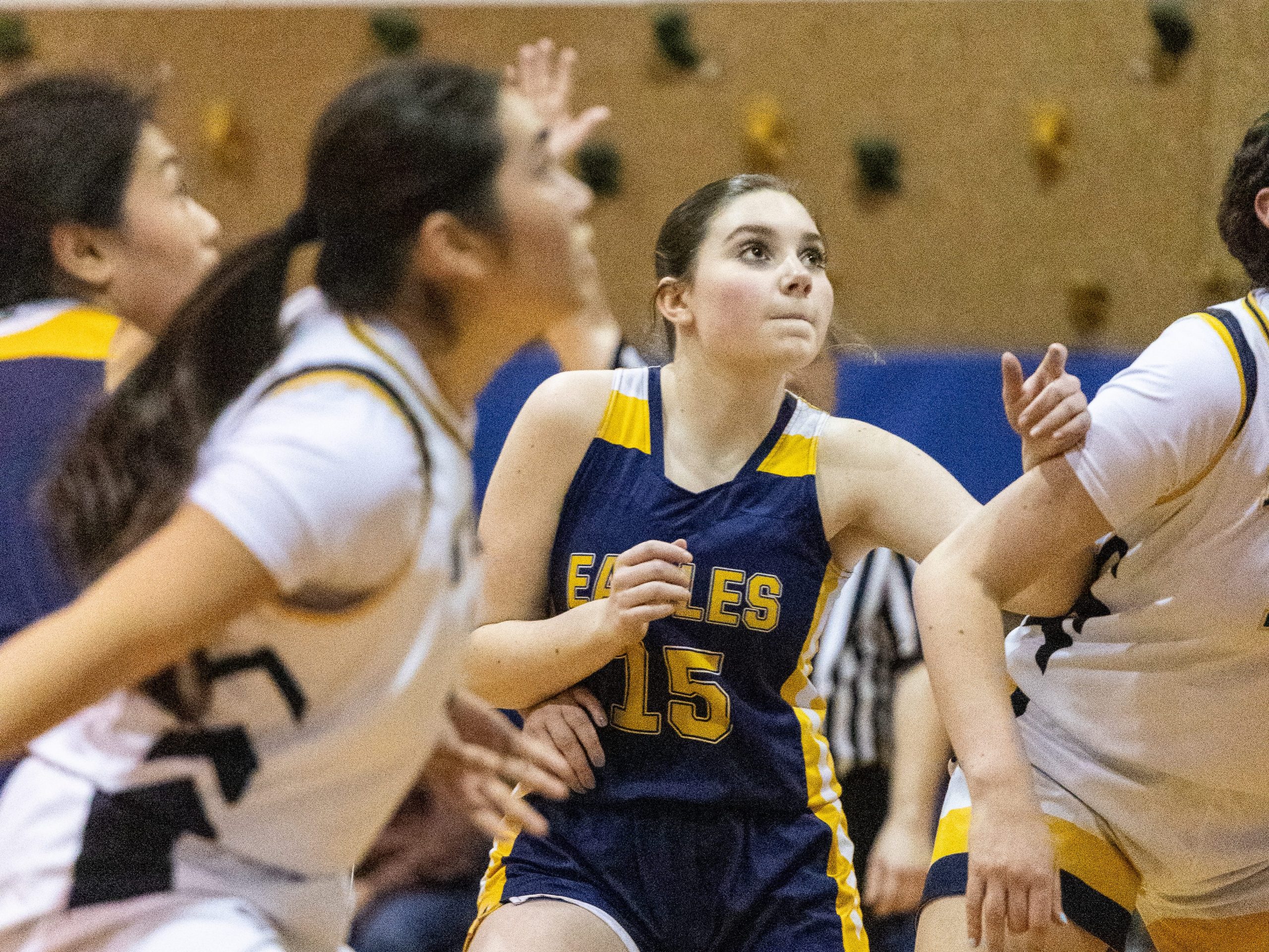 A girls basketball player looks for a rebound.