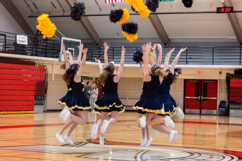 The cheer squad leaps in the air as part of their half-time routine.
